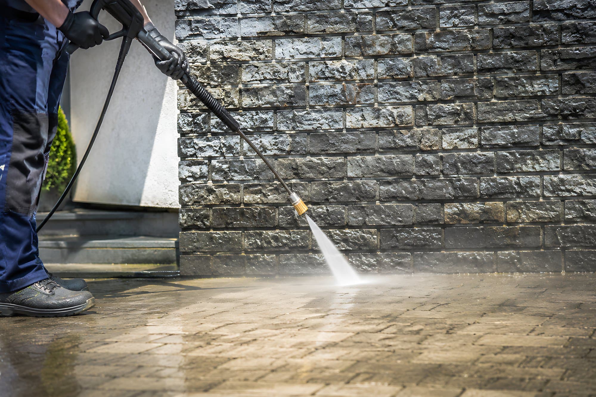 Jet washing a stone wall and wet block paving